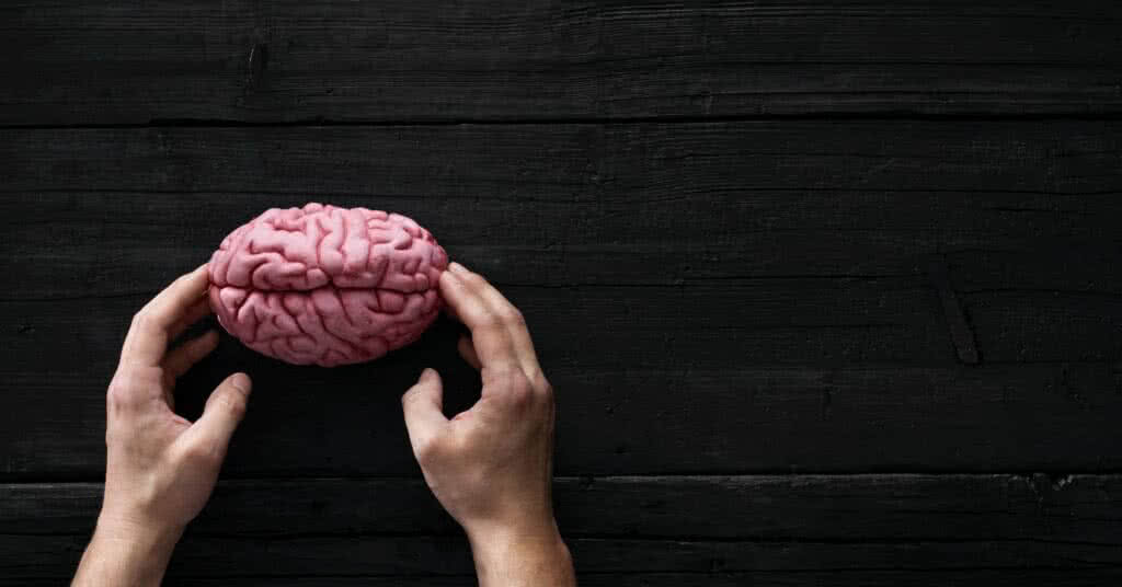 Mãos humanas tocando o cérebro: imagem ilustrativa para o artigo sobre o que causa o ataque isquêmico transitório (AVCI).
