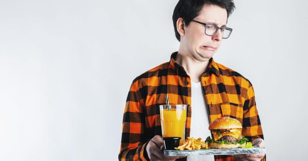 Homem bonito recusa hambúrguer não saudável em fundo branco - conceito de dieta.