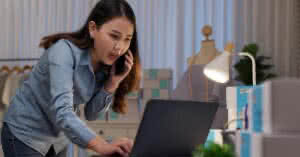 Mulher asiática triste e cansada, proprietária de uma loja online de moda, pensando no impacto da crise da Covid-19 em suas finanças e estoque. Esta imagem ilustra a situação de muitos empreendedores que enfrentam dificuldades financeiras durante a pandemia. Este post discute a relação entre Peixe Urbano e Groupon e como essas empresas podem ajudar pequenos negócios a superar a crise.